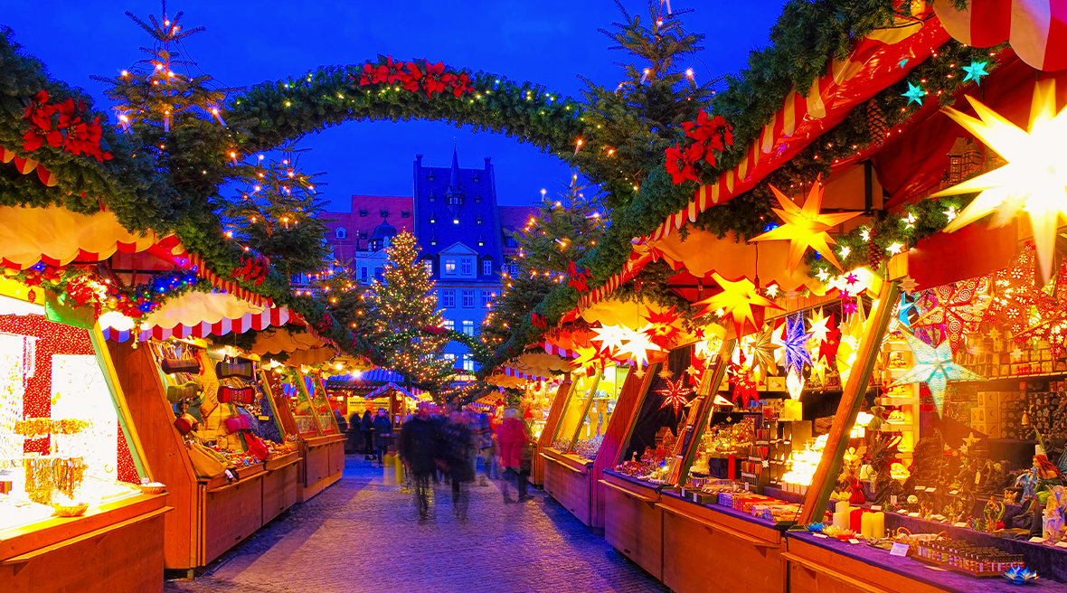 People walking between the decorated and lit stalls at Leipzig Christmas Market in the evening